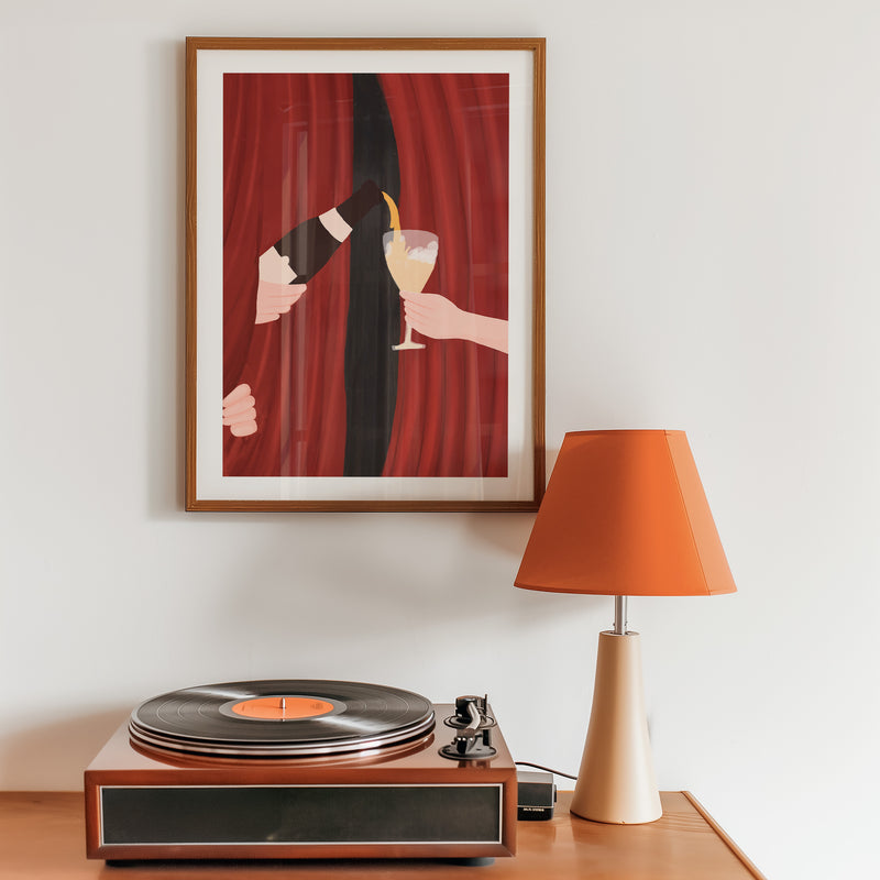 Framed artwork of a hand holding a glass with another hand reaching out against a red curtain background.